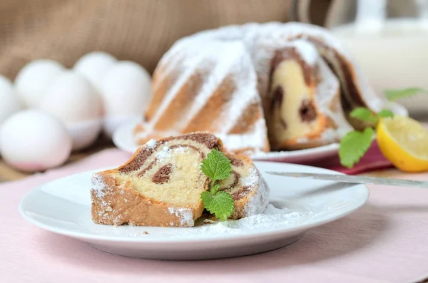 Skär marmor kaka beströs med socker, citron, melissa, mjölk, ägg och smör — Stockfoto