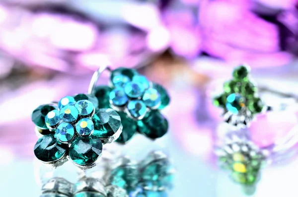 Крупный план зеленых сережек в форме цветка с бриллиантами ювелирные изделия - эффект отражения - кольцо на заднем плане — стоковое фото