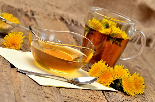 Miel de diente de león, té de hierbas, cuchara y diente de león alrededor — Foto de Stock