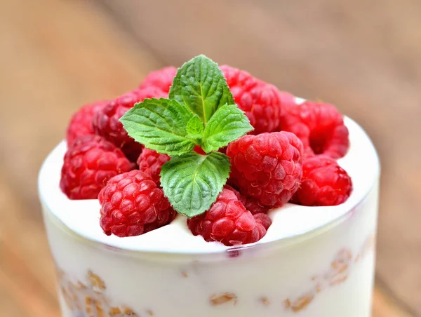 Nahaufnahme von griechischem Joghurt mit Haferflocken und frischen Himbeeren im Glas und Minzblättern — Stockfoto