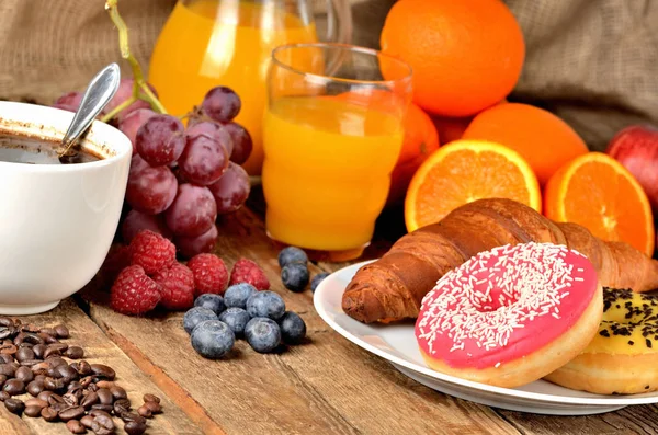 Kaffee, Donuts, Croissant, frisches Obst - Trauben, Orangen und Saft im Hintergrund — Stockfoto