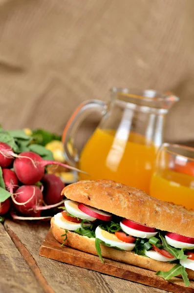 Baguette sandwich with egg, arugula salad, tomatoes and radish — Stock Photo, Image