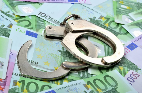 Αστυνομικές χειροπέδες στα τραπεζογραμμάτια ευρώ - έννοια της χρηματοδότησης και της εγκληματικότητας — Φωτογραφία Αρχείου