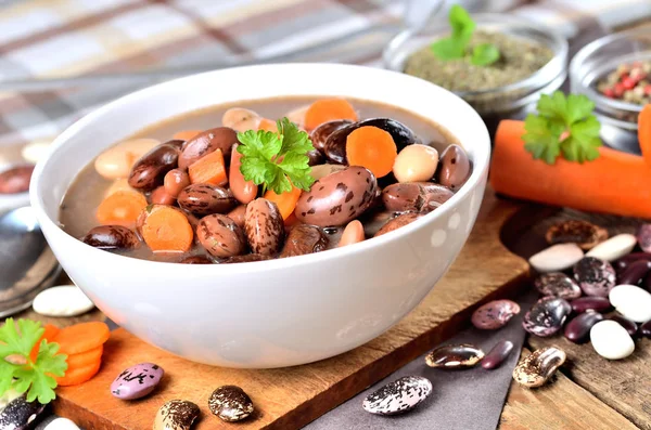 Bohnensuppe mit großen Bohnen auf Schneidebrett, Karotten, Petersilie, Majoran, Löffel und Schöpfkelle — Stockfoto