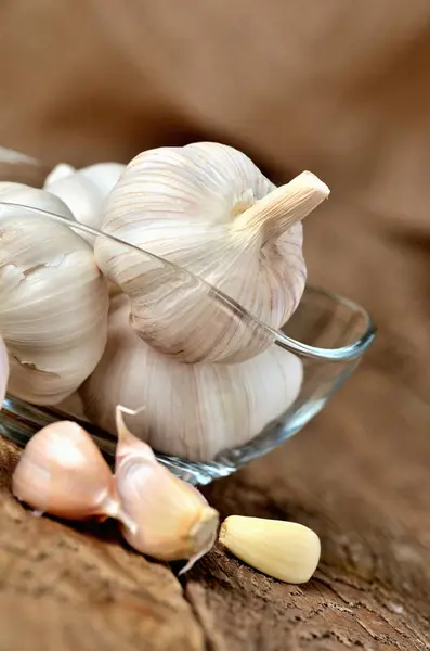 Bolbos de alho e cravos em lugares de vidro em tábuas de madeira rústica foto vertical — Fotografia de Stock