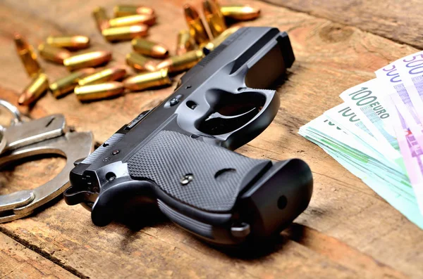 9mm-Handfeuerwaffe, Handschellen, Kugeln und Euroscheine auf altem Holztisch — Stockfoto