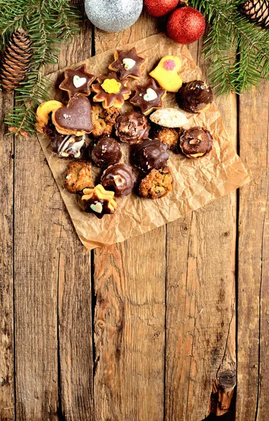 Visa från ovan av julgodis med olika typer av godis på bakplåtspapper och juldekorationer i vertikala bakgrundsfoto — Stockfoto