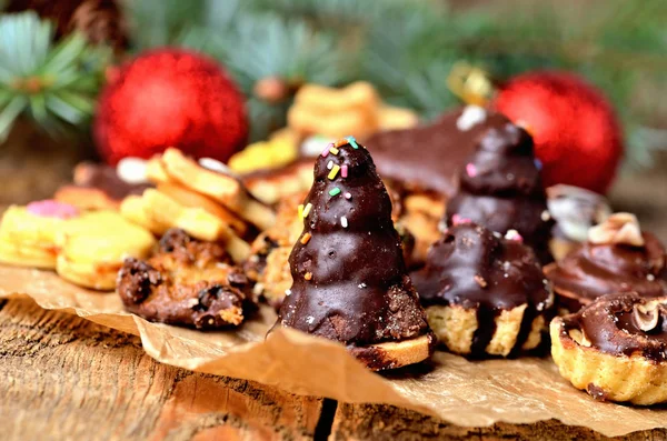 Різдвяні цукерки з різними видами цукерок на папері для випічки та різдвяні прикраси на фоні — стокове фото