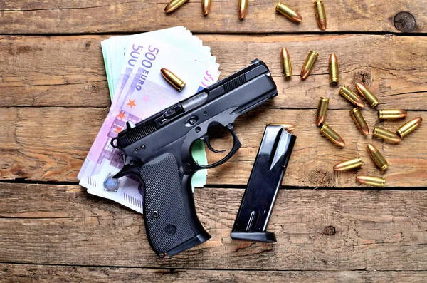 Κάτοψη του πιστόλι 9mm - περίστροφο, σφαίρες, τραπεζογραμμάτια ευρώ και το περιοδικό στο παλιό ξύλινο τραπέζι — Φωτογραφία Αρχείου