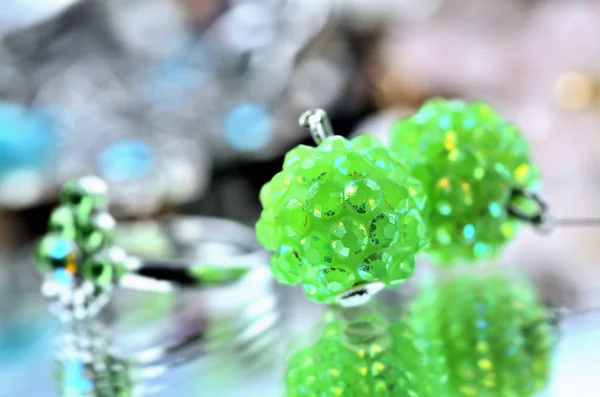 Nahaufnahme von grünen Ohrringen Schmuck - Reflexionseffekt - farbige Hintergründe — Stockfoto