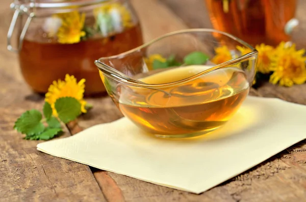 Gros plan de la confiture de pissenlit en verre, cuillère, tête de pissenlit autour et plein pot de confiture en arrière-plan — Photo