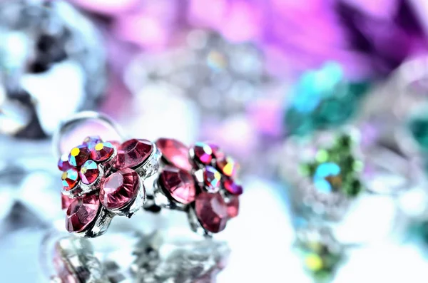 Nahaufnahme von roten blumenförmigen Ohrringen mit roten Diamanten und Ringschmuck - Reflexionseffekt - farbige Hintergründe - lila - kalte Farbbalance — Stockfoto