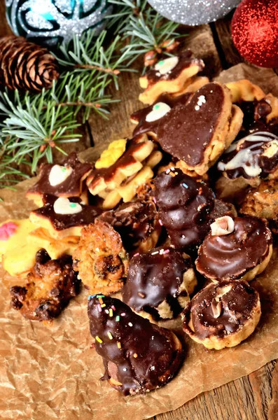 Dolci natalizi con diversi tipi di caramelle su carta da forno e decorazioni natalizie sullo sfondo — Foto Stock