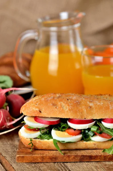 Baguette sandwich with egg, arugula salad, tomatoes and radish — Stock Photo, Image