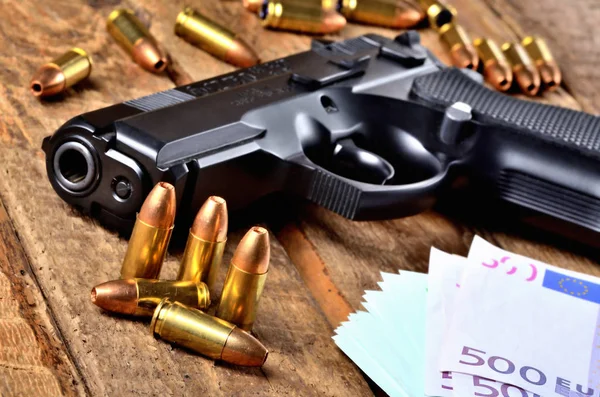 Close-up de pistola 9mm, balas especiais de ponto oco da polícia em expansão e notas de euro na velha mesa de madeira vista para o barril — Fotografia de Stock
