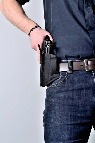 Man dra ut en pistol pistol från hölster på bältet, blå jeans, svart tröja — Stockfoto