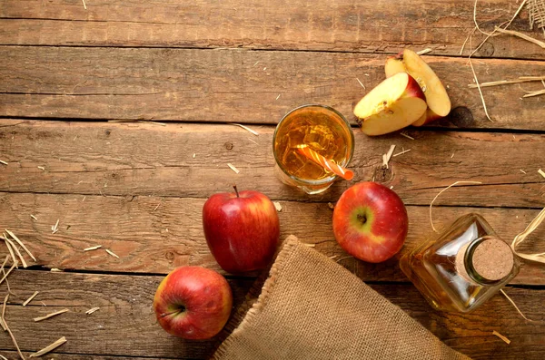 Pemandangan dari atas jus apel buatan sendiri dengan es, apel merah, jerami, masih hidup di atas meja kayu — Stok Foto