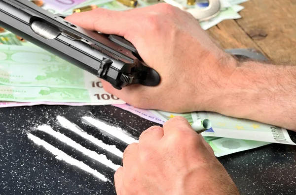コカイン ローラー紙幣を使用し、一方、バック グラウンドでユーロ紙幣でピストル銃男 — ストック写真