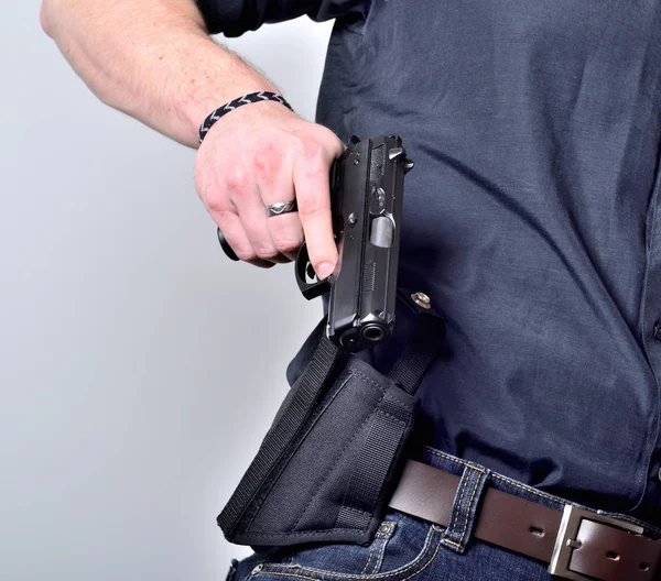 Närbild av mans hand att dra ut en pistol pistol från hölster på bältet, blå jeans, svart tröja — Stockfoto