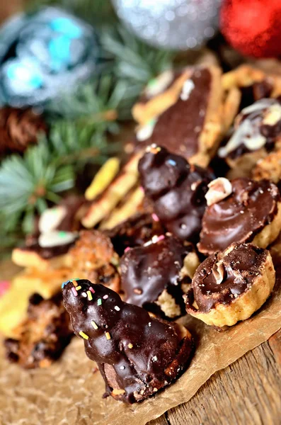 Julgodis med olika typer av godis på bakning papper och juldekorationer i bakgrunden — Stockfoto