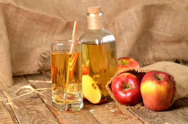 Jus dari apel, jerami, es dan botol segar di latar belakang papan kayu — Stok Foto