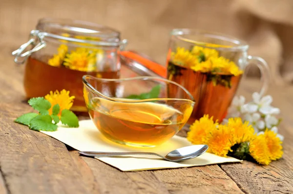 Dandelion honey, herbal tea, full jar of honey, spring flower, fresh mint leaves, spoon and dandelion head around — Stock Photo, Image