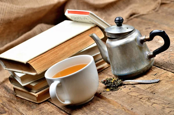 Stack of vintage books, cup of black tea, old teapot and spoon with tea loose — Stock Photo, Image