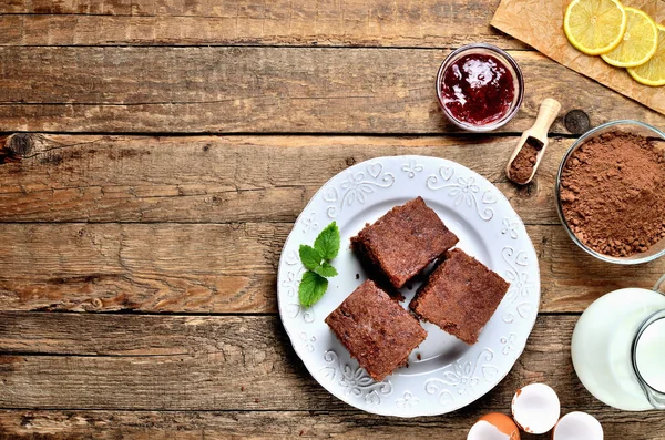 Traditionelle tschechische Lebkuchen, getrocknete Zitronenstücke, Kakaopulver, Eierschalen, Milchkrug und Himbeermarmelade auf weißem Teller. Blick von oben. — Stockfoto