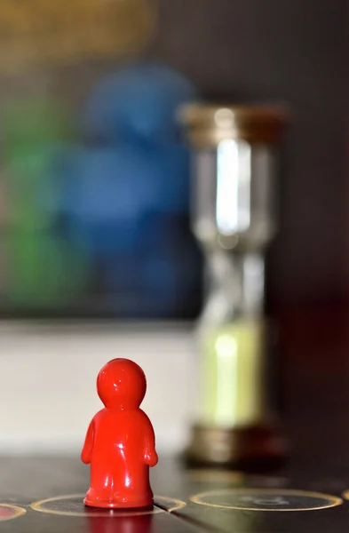 Ampulheta com areia e figura de jogo vermelho no campo de jogo para jogos de tabuleiro . — Fotografia de Stock