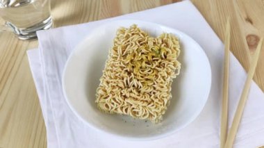 Baharatlı tabakta yumurtalı şehriye. Anında ramen çorbası. Evde fast food pişirmek, kasede bir parça kuru erişte. Yakın plan, ahşap masa, beyaz peçete, çubuklar, 4k.