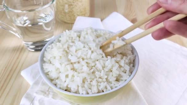 炊いた白飯を箸で丸めて盛り付けます お皿からゆっくりとした長粒米を食べる 簡単な食事 アジア料理 クローズアップ 木製のテーブル ナプキン — ストック動画