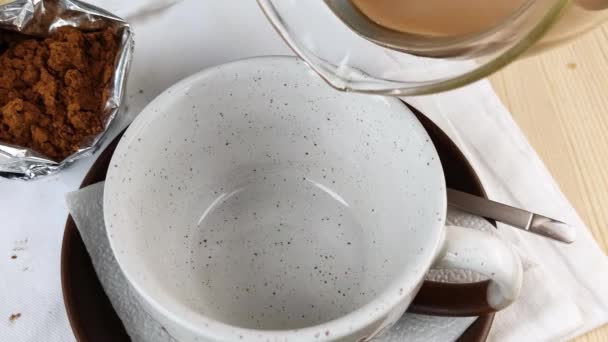 可可饮料倒入杯子 勺子倒入茶托 天然美味的热巧克力 早餐时选用健康的咖啡因 特写侧视图 木制桌子 白色餐巾 可可粉包装 — 图库视频影像