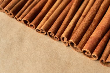 Tarçın çubukları kağıt üzerinde. Çapraz kompozisyon, yakın plan. Yemek pişirmek için baharatlı malzeme, aromaterapi. Kopya uzayı olan yatay pankart. Doğal organik ekolojik ürün. Tek renkli kahverengi desen