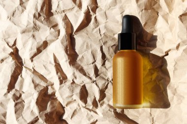 Kraft kağıdında kozmetik yağ şişesi. Yatay maketler. Tek renkli kahverengi pankart, boşluğu kopyala. Ginger şişesi, nemlendirici emülsiyon, serum, jel. Deri hidrasyonu, vücut bakımı konsepti. Sert ışık