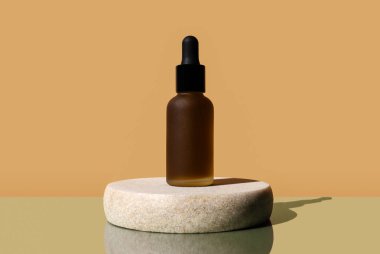 Buzlu aroma yağı şişesi, granit kaide. Model, poster, afiş. Esmer şişede kenevir özü, bitkisel emülsiyon, serum. Doğal organik kozmetik, aromaterapi. Merkezi kompozisyon, bej arkaplan