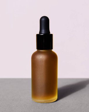 Gri pembe arka planda siyah pipetli cam yağ şişesinin dikey modeli. Pankart şablonu, poster. Sarı kahverengi losyonlu güzel şekerli şişe. Organik eko kozmetik serumu, özü, emülsiyonu