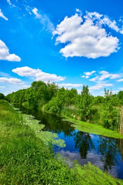 Berlin, Almanya 'nın çevresindeki küçük bir derenin üzerinde mavi ve bulutlu bir gökyüzü.