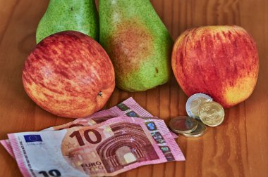 Meyve, Avrupa banknotları ve paralarla birlikte ahşap bir arka planda yatıyor..