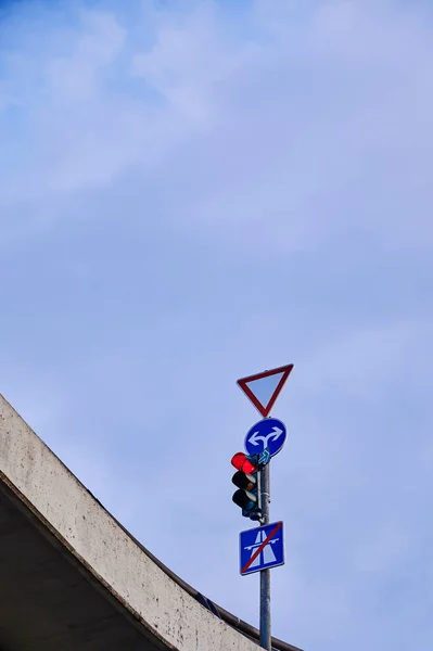 Bottom view of a red traffic light and various traffic signs at an intersection on a bridge in Berlin, Germany.