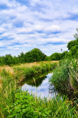 Berlin, Almanya 'nın çevresindeki küçük bir derenin üzerinde bulutlu bir gökyüzü.