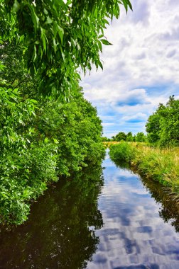 Berlin, Almanya 'nın çevresindeki küçük bir derenin üzerinde bulutlu bir gökyüzü.