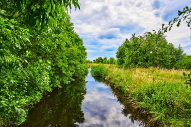 Berlin, Almanya 'nın çevresindeki küçük bir derenin üzerinde bulutlu bir gökyüzü.