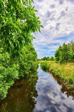 Berlin, Almanya 'nın çevresindeki küçük bir derenin üzerinde bulutlu bir gökyüzü.