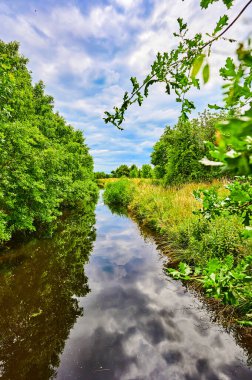 Berlin, Almanya 'nın çevresindeki küçük bir derenin üzerinde bulutlu bir gökyüzü.