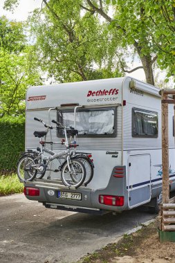 Berlin, Almanya - 28 Temmuz 2020: Arkasına iki bisikletli bir bisiklet taşıyan park edilmiş beyaz bir karavan.
