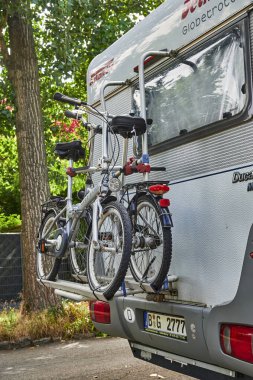 Berlin, Almanya - 28 Temmuz 2020: Arkasına iki bisikletli bir bisiklet taşıyan park edilmiş beyaz bir karavan.