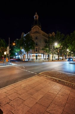 Berlin, Almanya - 16 Ağustos 2020: Berlin şehir merkezindeki Kurfrstendamm kavşağında geçen arabaların aydınlatılmış binaları ve ışık efektleriyle gece görüntüsü.