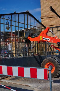 Berlin, Almanya - 9 Nisan 2020: Dresden demiryolu hattında inşaat alanı. Eski bir cam bisiklet kulübesini söken işçilere destek veren bir kazıcı görüyorsunuz..