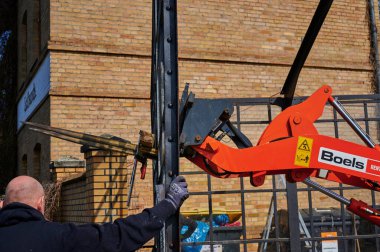 Berlin, Almanya - 9 Nisan 2020: Dresden demiryolu hattında inşaat alanı. Eski bir cam bisiklet kulübesini söken işçilere destek veren bir kazıcı görüyorsunuz..