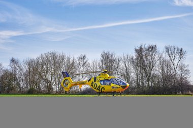 Berlin, Almanya - 18 Mart 2020: Bölgeye sağlık personeli getirmek için bir çayıra inen sarı kurtarma helikopteri.